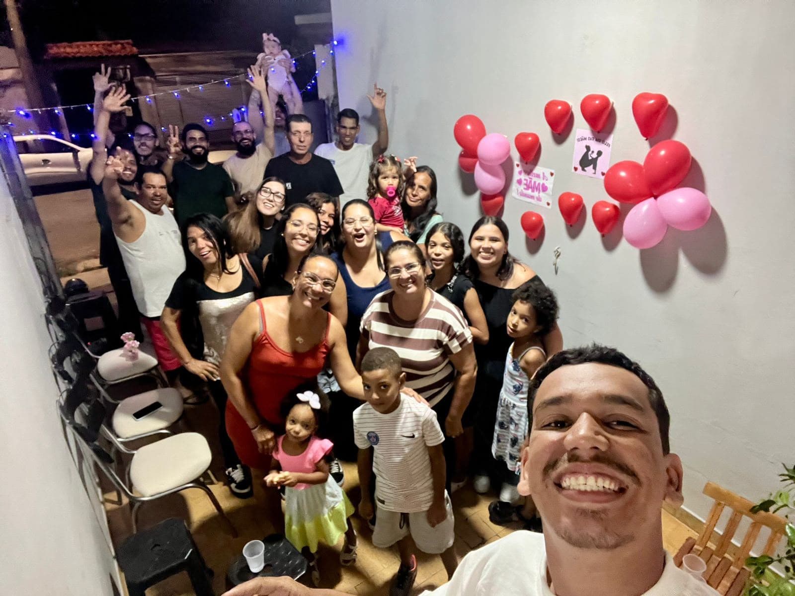 Célula reunida numa varanda decorada com balões vermelhos, adultos e crianças juntos