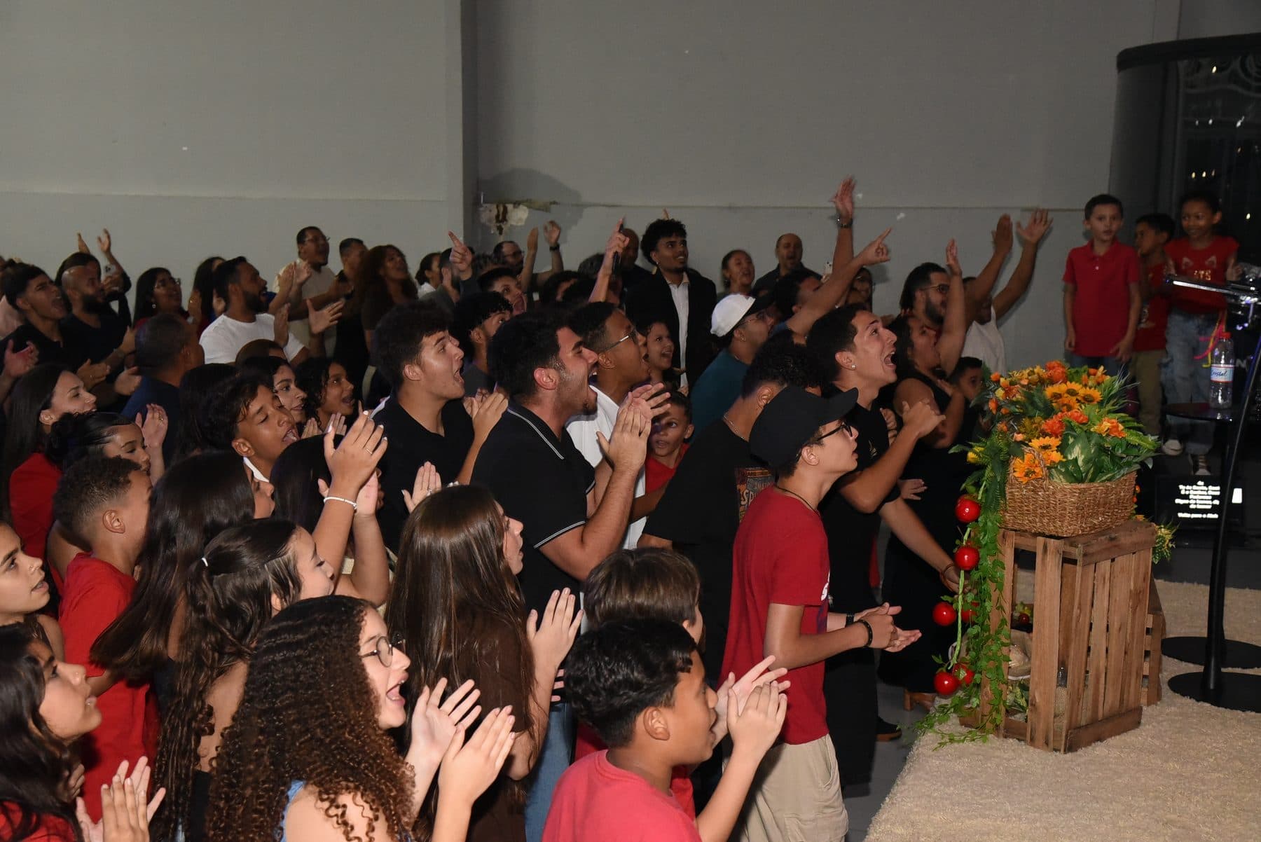 Congregação da Videira de pé num culto de domingo, cantando de mãos erguidas