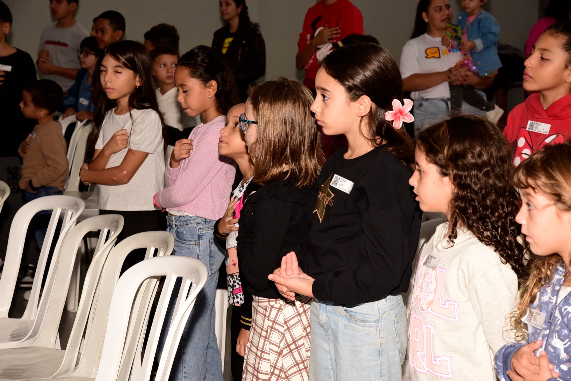 Crianças do Radicais Kids em pé, em oração, durante o culto