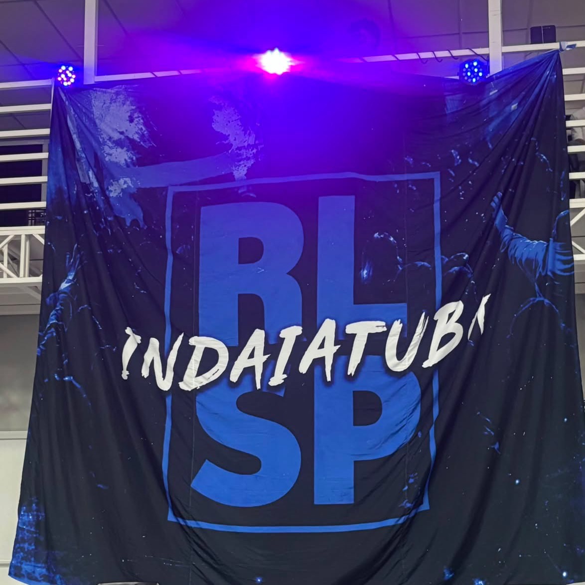Bandeirão dos Radicais Livres de Indaiatuba pendurado no ginásio, iluminado por refletores azuis
